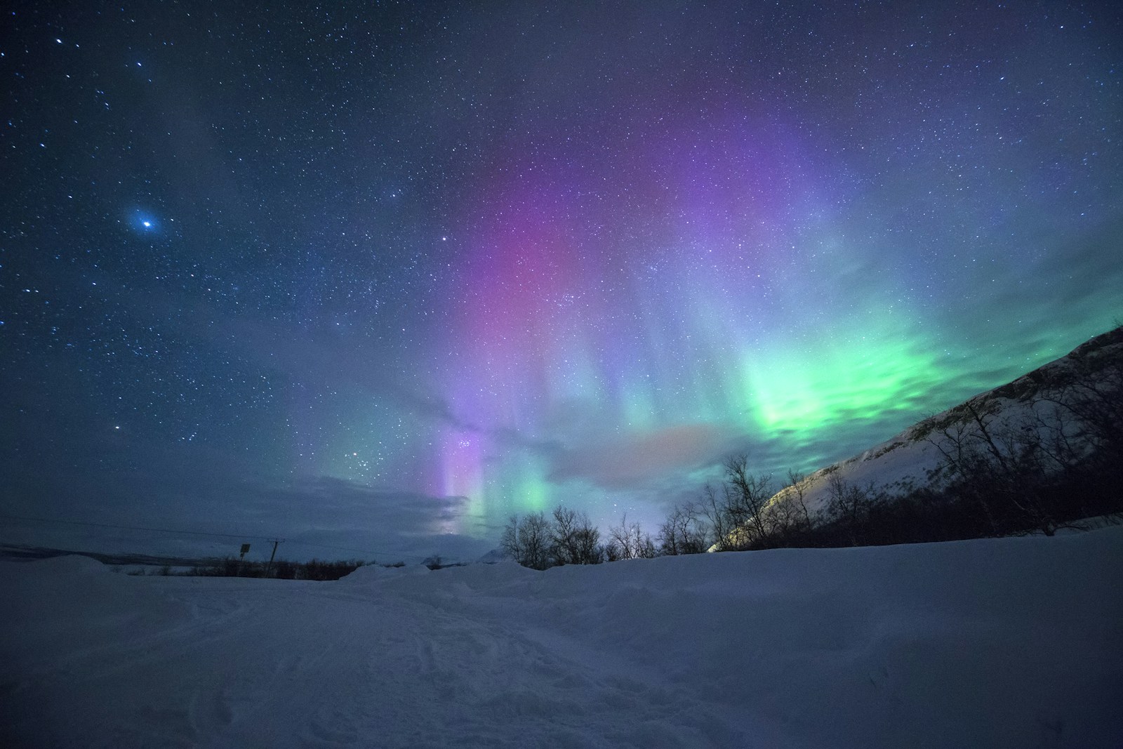Northern lights above a snow-covered mountain landscape